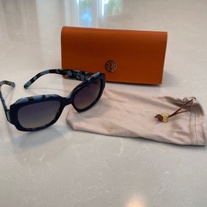 Tory Burch sunglasses, orange case and beige soft drawstring bag.